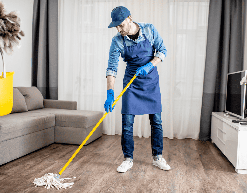 Professional cleaner mopping floor with cleaning supplies during recurring house cleaning visit